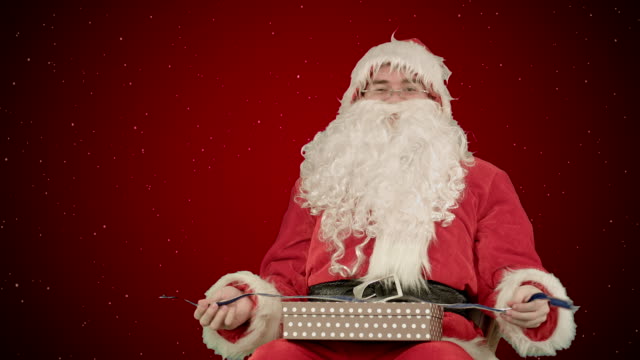 Santa-Claus-sosteniendo-regalos-de-Navidad-sobre-fondo-rojo-con-nieve