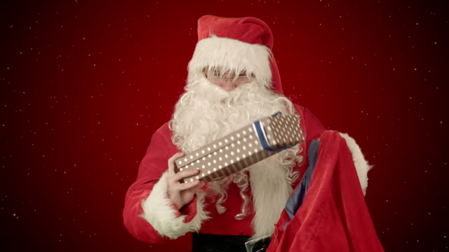 Echter-Weihnachtsmann-trägt-Geschenke-in-seinem-Sack-auf-rotem-Hintergrund-mit-Schnee
