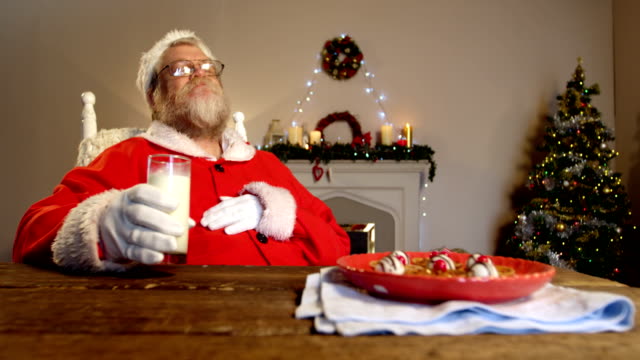 Santa-Claus-am-Stuhl-zu-entspannen-und-mit-süßen-Speisen