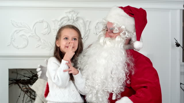 Santa-Claus-sitting-in-a-chair-with-a-little-girl-dreaming-about-her-Christmas-presents