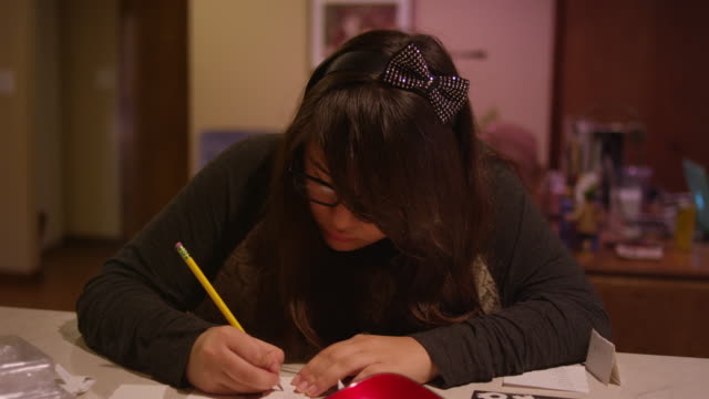 Ein-Mädchen-sitzt-an-einem-Küchenschalter-und-schreibt-auf-einem-Blatt-Papier