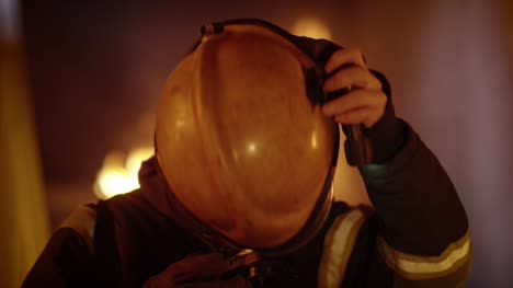 Building-is-on-Fire.-Brave-Fully-Equipped-Firefighters-Takes-off-His-Helmet.-Open-Flames-in-the-Background.-Slow-Motion.
