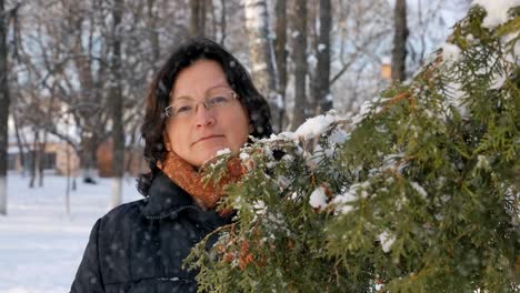 Eine-junge-Frau-in-einem-Park-mit-Tanne-auf-der-Straße,-Hände-berühren-die-Ästen-der-Bäume,-untersuchen.-Saison-winter