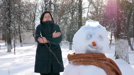 Young-Woman-Building-Snowman-in-the-Park.-In-the-winter