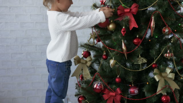Niedliche-kleine-Mädchen-schmückt-den-Weihnachtsbaum.