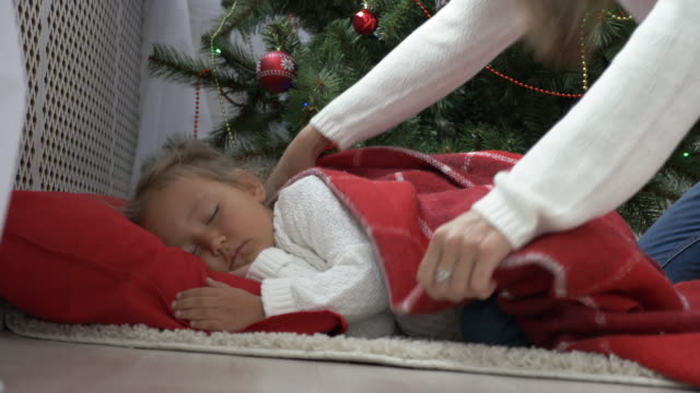 Cute-little-girl-sleeping-under-Christmas-tree-at-morning