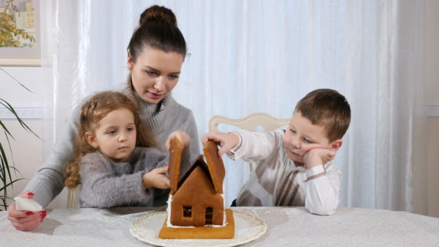 Schöne-Frau-mit-kleinen-Kindern-macht-ein-Lebkuchenhaus