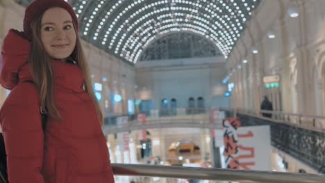 beautiful-young-woman-is-walking-through-the-big-shopping-mall-in-Moscow.-Blurry-background-with-beautiful-lights.