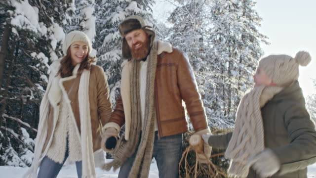 Junge-und-Eltern-tragen-Weihnachtsbaum-aus-Wald
