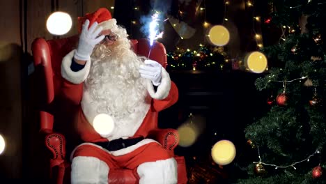 Agradar-a-Papá-Noel-se-sienta-en-su-silla-delante-de-un-árbol-de-Navidad.