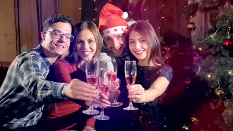 Portrait-of-4-cheerful-friends-at-new-year-christmas-party-looking-into-camera-holding-glasses-with-champagne.
