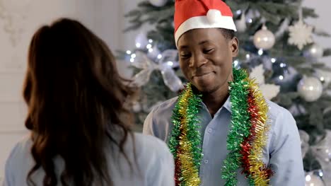 Man-in-Santa-hat-gives-a-gift-for-woman-on-Christmas-holiday