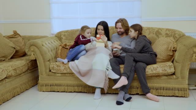 Happy-family-with-christmas-gift-at-the-sofa-at-home