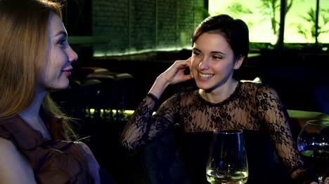 Two-beautiful-cheerful-girls-laughing-talking-at-the-bar-over-drinks