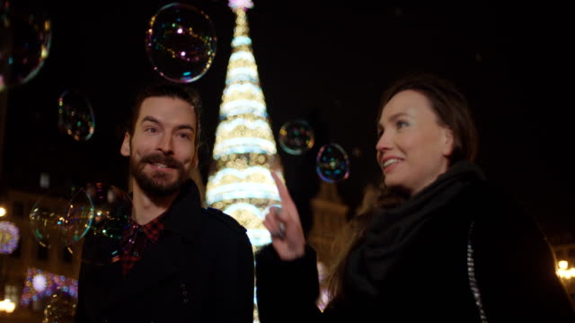 Beautiful-couple-having-fun-among-big-soap-bubbles-in-a-city-at-night.