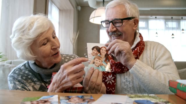 Senior-pareja-mostrando-la-foto-de-los-niños-en-la-mesa-de-restaurante