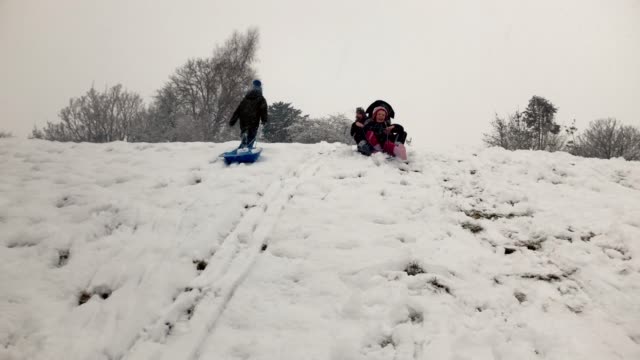 Mother-and-daughter-sledging-down-a-snowy-hillside