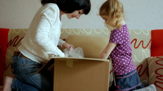 Family,-Mom-and-Daughter-opens-the-parcel-from-the-online-store.-Young-woman-looks-in-the-box,-is-surprised-and-happy-to-receive-a-surprise.-Girl-opened-a-box-with-a-gift.-Slow-Motion.