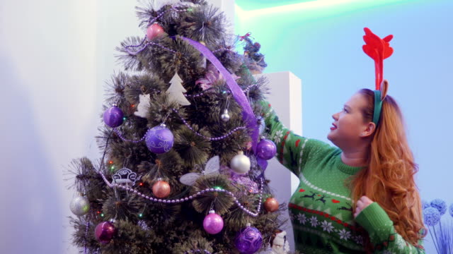 Girl-look-Christmas-tree-decoration-and-play-with-long-hair