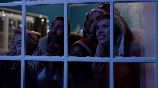 Excited-friends-looking-out-in-window-during-Christmas