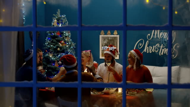 Blick-durchs-Fenster-von-Menschen-feiern-Weihnachten