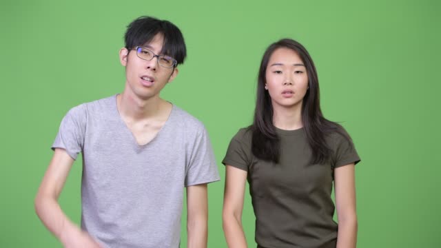 Young-Asian-couple-giving-thumbs-down-together