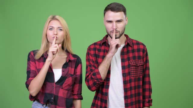 Young-couple-with-finger-on-lips-together