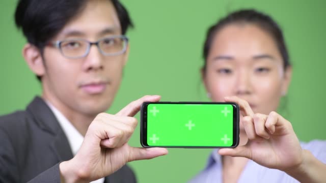 Jóvenes-asiáticos-par-mostrar-teléfono-junto