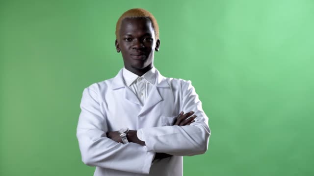 Young-african-blond-doctor-in-white-coat-and-glasses-looking-at-camera,-standing-alone-on-chromakey-background,-confident-and-successful