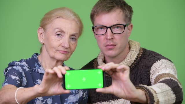 Glückliche-Großmutter-und-Enkel-zeigt-Handy-zusammen