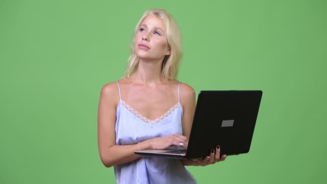 Young-happy-beautiful-businesswoman-thinking-while-using-laptop