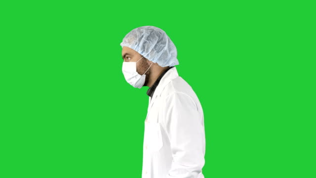 Doctor-apuesto-con-su-uniforme-y-con-una-máscara-está-caminando-sobre-una-pantalla-verde-Chroma-Key