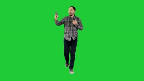 Man-calling-via-video-call-on-phone-talking-to-someone-waving-hello-during-videochat-conversation-on-a-Green-Screen,-Chroma-Key