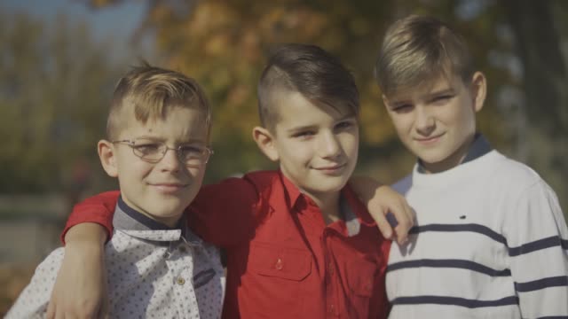 Three-young-boys-smiling-and-hugging-outdoors.-Brothers-spend-time-together.