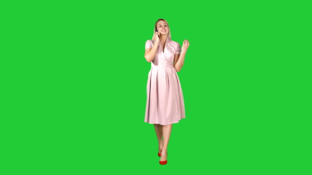 Happy-smiling-woman-talking-on-cell-phone-while-walking-on-a-Green-Screen,-Chroma-Key
