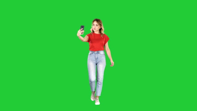 Linda-chica-sexy-con-el-pelo-rizado-rubio-caminando-y-haciendo-selfie-en-una-pantalla-verde-Chroma-Key