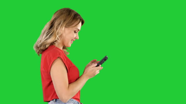 Glücklich-niedlich-schöne-junge-Frau-spielen-mit-dem-Handy-auf-einem-Green-Screen,-Chroma-Key