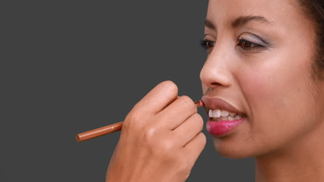 Maquilladora-putting-gloss-de-labios-en-modelos-de-cara
