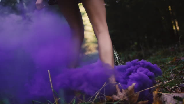 Beautiful-girl-in-a-dress-spins-around-in-purple-smoke-from-a-color-smoke-grenade,-slow-motion