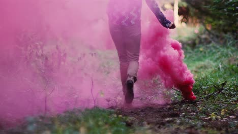 Schönes-Mädchen-in-einem-Wald-läuft-durch-rosa-Rauch-von-einer-Farbe-Rauch-Granate,-Zeitlupe
