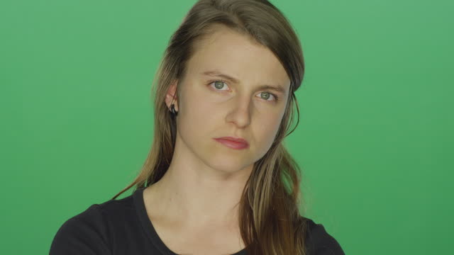 Young-women-looks-upset-and-shakes-her-head,-on-a-green-screen-studio-background