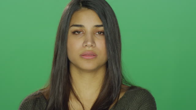 Young-woman-starting-to-recover-after-crying,-on-a-green-screen-studio-background
