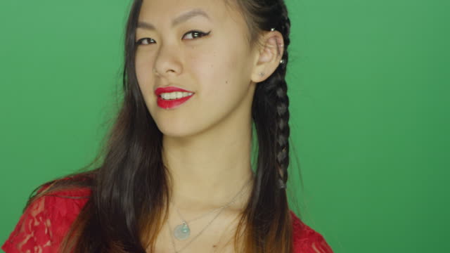 Young-Asian-woman-staring-and-looking-sexy,-on-a-green-screen-studio-background