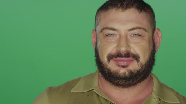 Muscular-man-attempts-to-make-silly-faces,-on-a-green-screen-studio-background