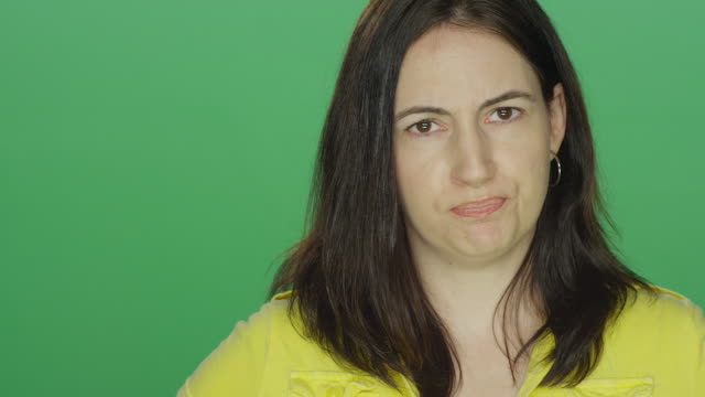 Young-brunette-woman-looking-really-upset,-on-a-green-screen-studio-background