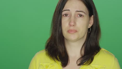 Young-brunette-woman-begins-to-tear-up,-on-a-green-screen-studio-background