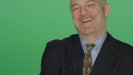 Middle-aged-businessman-smiling-and-laughing,-on-a-green-screen-studio-background