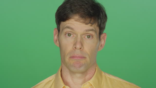 Middle-aged-man-looking-sad,-on-a-green-screen-studio-background