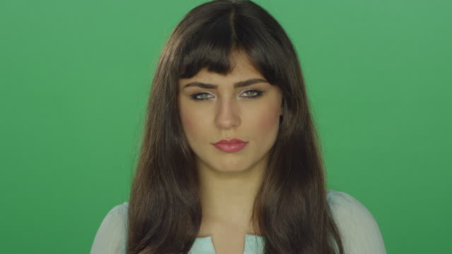 Tired-beautiful-brunette-woman-looking-slightly-concerned,-on-a-green-screen-studio-background