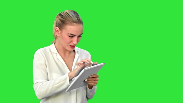 Businesswoman-standing-with-digital-tablet,-touching-the-screen-and-smiling-on-a-Green-Screen,-Chroma-Key
